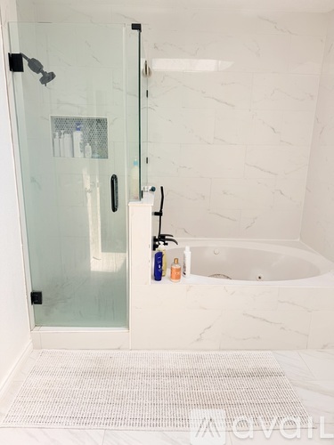 A white bathroom with a glass shower door and a white tub.