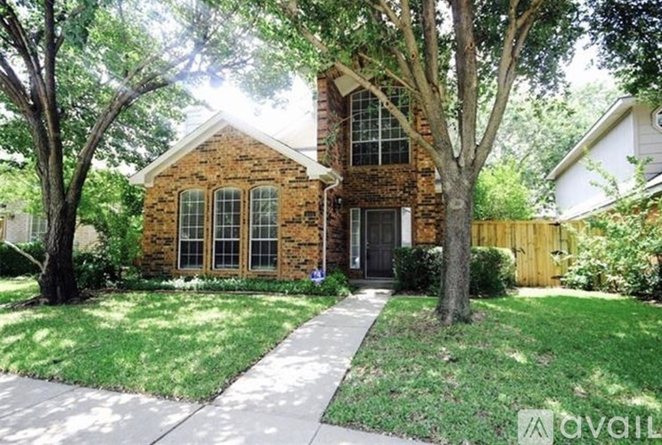 A brick house with a black door and a tree in front.