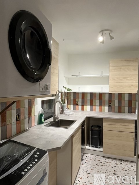 A kitchen with a sink, dishwasher, and a round mirror on the wall.