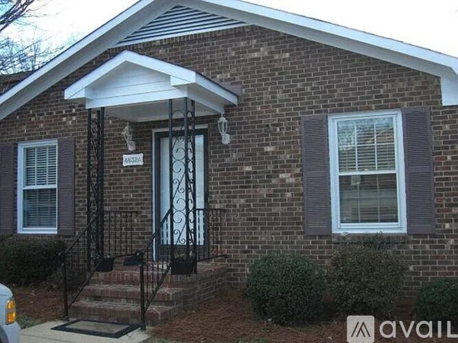 A brick house with a black door and window shutters.