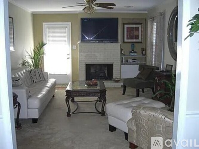 A living room with a fireplace and a television mounted above it.