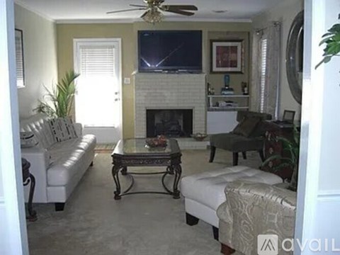 A living room with a fireplace and a television mounted above it.