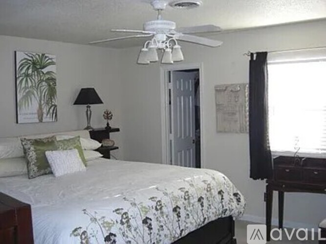 A bedroom with a bed, a ceiling fan, and a window.
