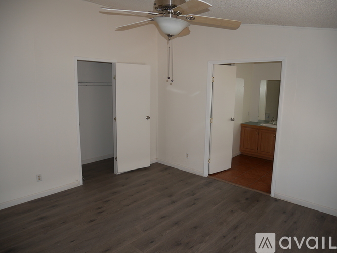 A room with a ceiling fan and wooden flooring.
