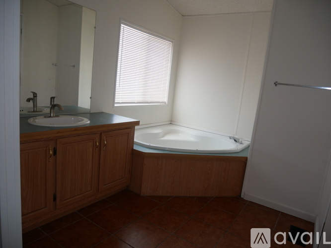 A bathroom with a tub, sink, and wooden cabinets.