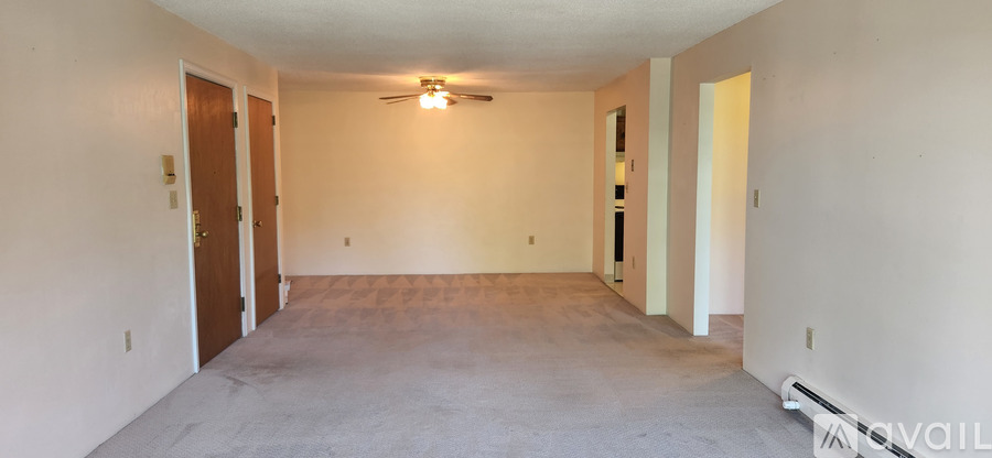 A spacious room with a ceiling fan and two doors.