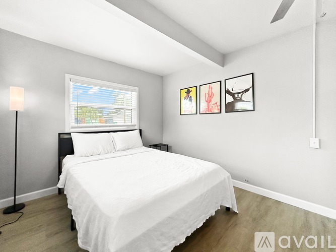 A bedroom with a bed, nightstand, lamp, and pictures on the wall.