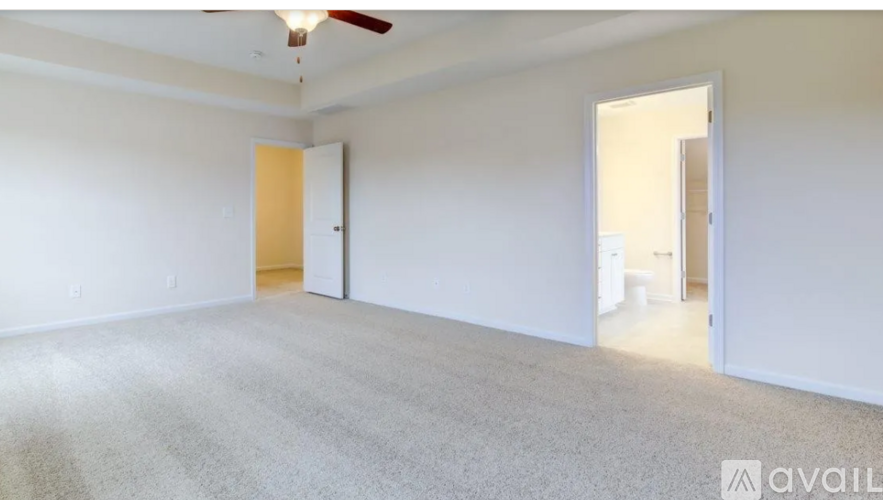 A room with a carpeted floor and a ceiling fan.