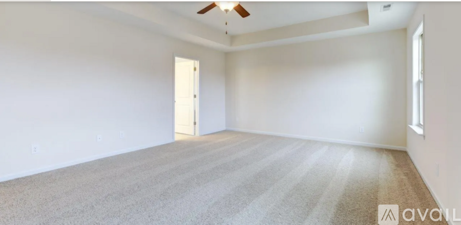 A spacious room with a carpeted floor and a ceiling fan.