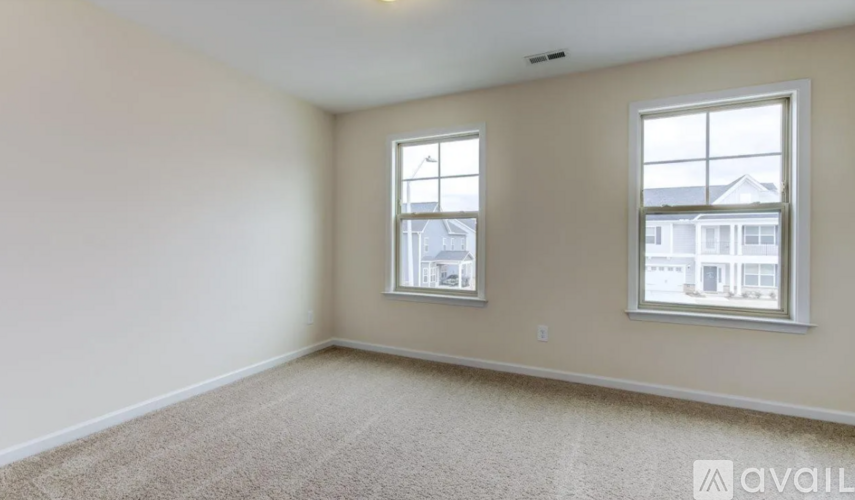 A room with two windows and carpeted floor.