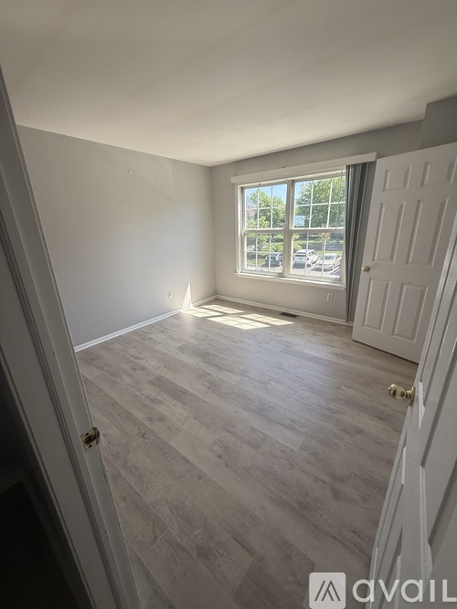 A room with a door and a window overlooking a parking lot.