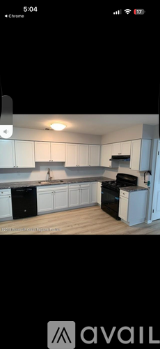 A kitchen with white cabinets and black appliances.