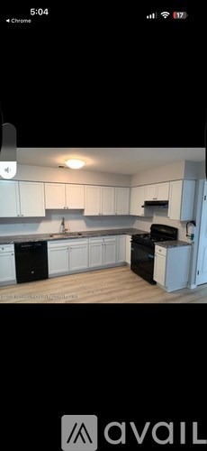 A kitchen with white cabinets and black appliances.