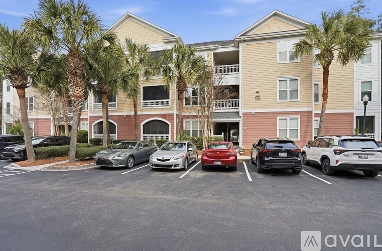 A parking lot with several cars and a building in the background.