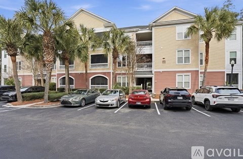 A parking lot with several cars and a building in the background.