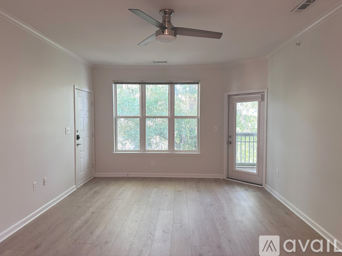 A room with a ceiling fan and a window with a view of trees.