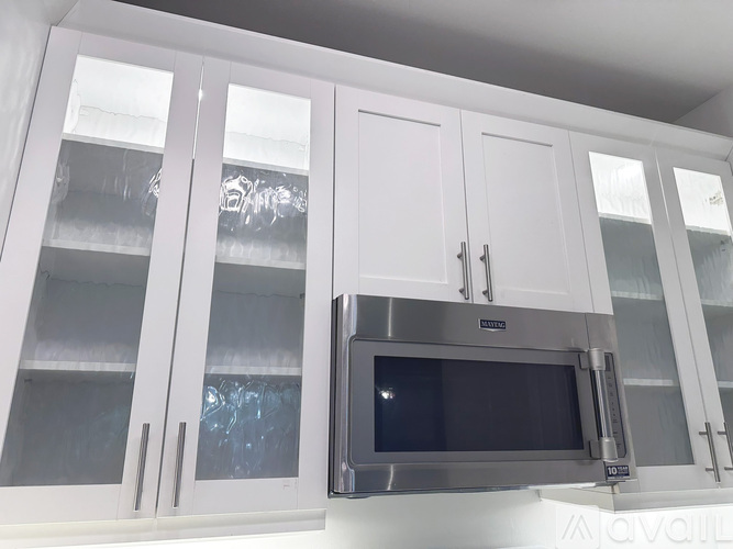 A white kitchen with a microwave oven installed above the counter.