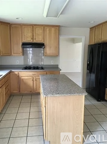 A kitchen with wooden cabinets and a black refrigerator.