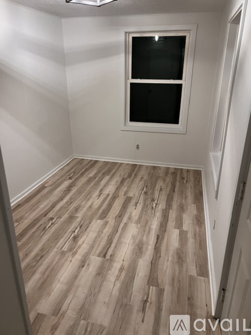 A room with a window and wooden flooring.