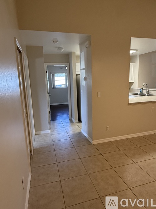 A hallway with a door at the end and a kitchen area to the right.