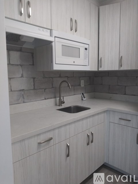 A kitchen with white cabinets and a microwave above the sink.
