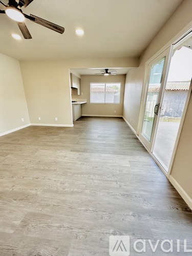 A spacious room with a ceiling fan and sliding glass doors.