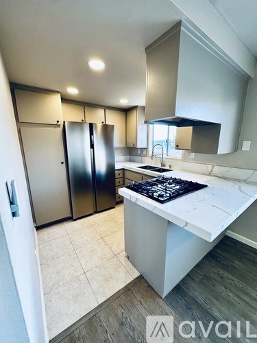 A kitchen with a white countertop and a black stove top.