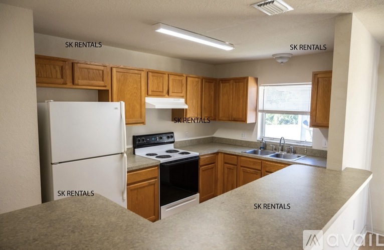 A kitchen with wooden cabinets and a white fridge is for rent.