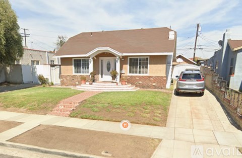 A house with a brown roof and a white door is surrounded by a green lawn.