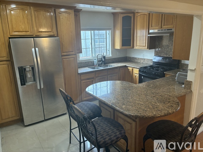 A kitchen with granite countertops and a stainless steel refrigerator.