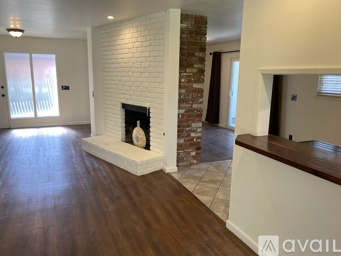 A living room with a fireplace and wooden floors.