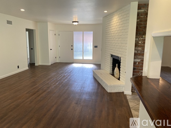 A spacious living room with a fireplace and wooden floors.