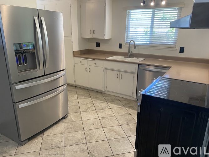 A kitchen with a stainless steel refrigerator and white cabinets.