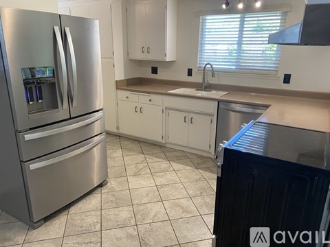 A kitchen with a stainless steel refrigerator and white cabinets.