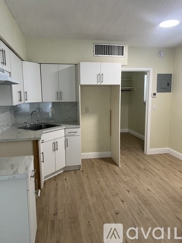 A kitchen with white cabinets and a marble countertop.