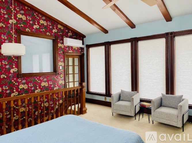 A bedroom with a floral wallpapered wall and a bed in the foreground.