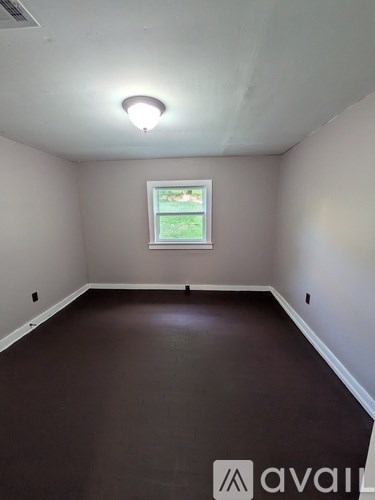 A room with a window and a brown floor.