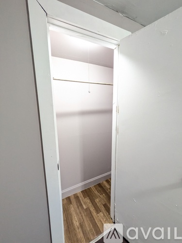 A white doorway leading to a room with wooden flooring.