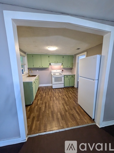 A kitchen with white appliances and green cabinets.