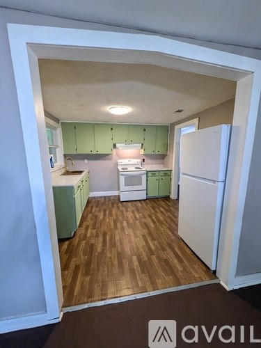 A kitchen with white appliances and green cabinets.
