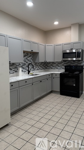A kitchen with white cabinets and black appliances.