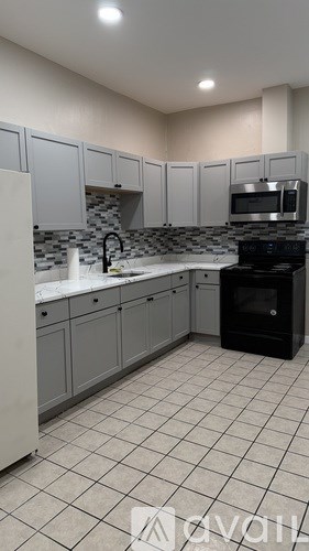 A kitchen with white cabinets and black appliances.