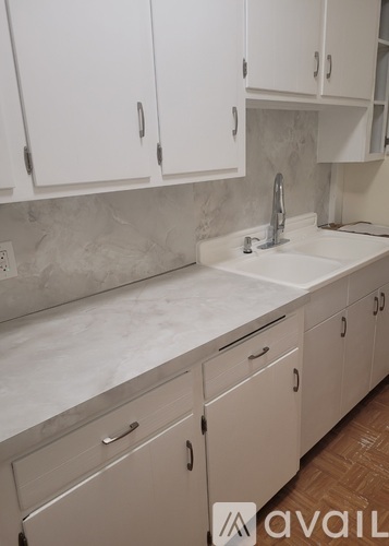 A kitchen with white cabinets and a marble countertop.