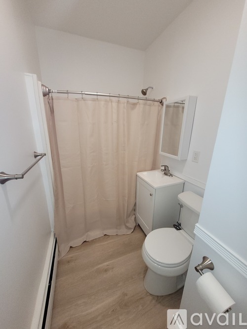 A small bathroom with a toilet, a shower curtain, and a towel rack.