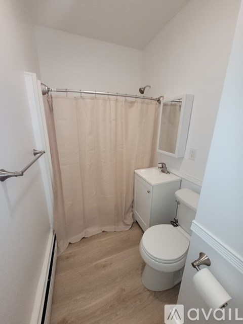A small bathroom with a toilet, a shower curtain, and a towel rack.