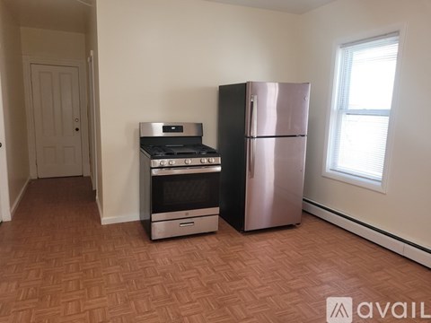 A kitchen with a stove, oven, and refrigerator in a room with a door and window.