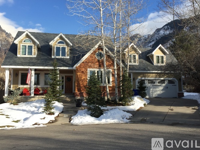 A house with a mountain in the background and snow on the ground.
