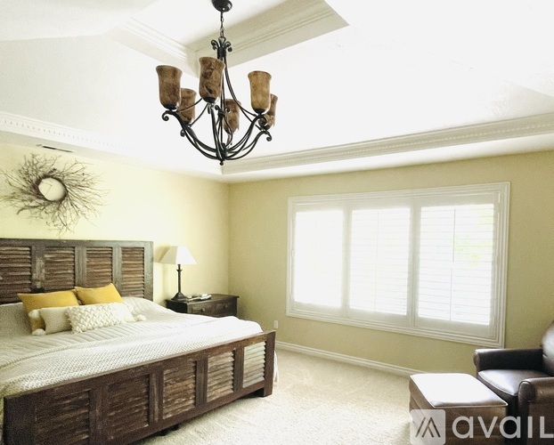 A bedroom with a large bed and a chandelier.