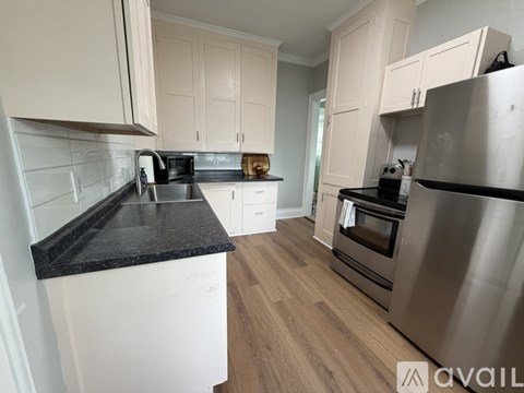 A kitchen with white cabinets and a black countertop.