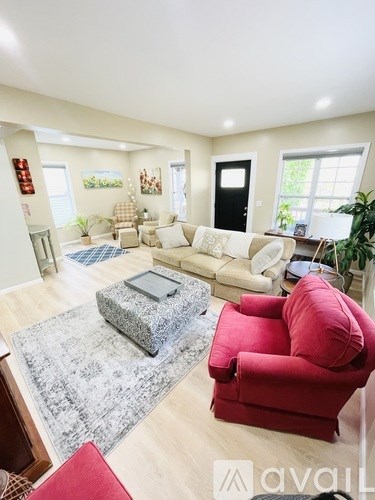 A living room with a red chair and a grey ottoman.